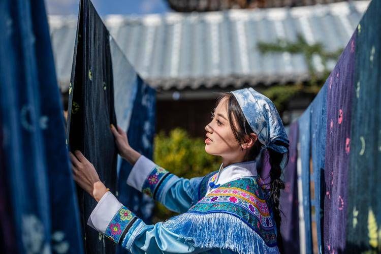 Caption: A woman experiences the tie-dye technique of Bai ethnic groupin a dyehouse in Zhoucheng Village of Dali Bai Autonomous Prefecture, southwest China's Yunnan Province, Nov. 21, 2025.(Xinhua/Hu Chao)