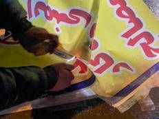 Una persona usa un accendino per dare fuoco a uno striscione durante le manifestazioni a Hamedan - Ipa