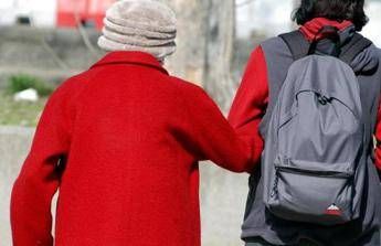 Una signora anziana viene accompagnata ad attraversare la strada (Fotogramma/Ipa)