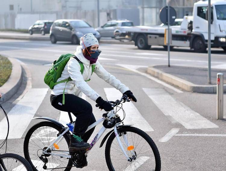 Donna in bici con mascherina anti-smog (Fotogramma)