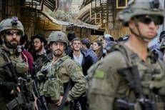 Militari israeliani scortano dei coloni nel mercato di Hebron, in Cisgiordania - Fotogramma/Ipa