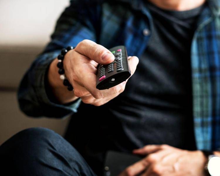Persona cambia canale con telecomando - (123Rf)
