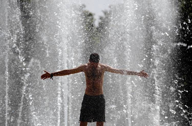 Uomo si rinfresca sotto fontana - (Afp)