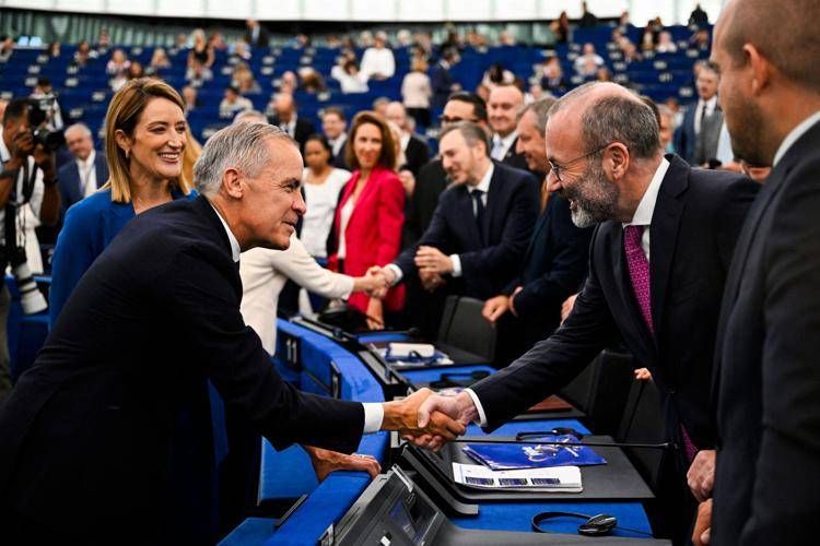 Il leader del Ppe Manfred Weber (a destra) stringe la mano al presidente del Canada all'Europarlamento a Soteu 2026 - (Afp)