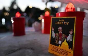 Un'immagine di Papa Leone XIV e alcune candele deposte ai piedi della statua di Giovanni Paolo II, davanti al Policlinico Gemelli - (Afp)
